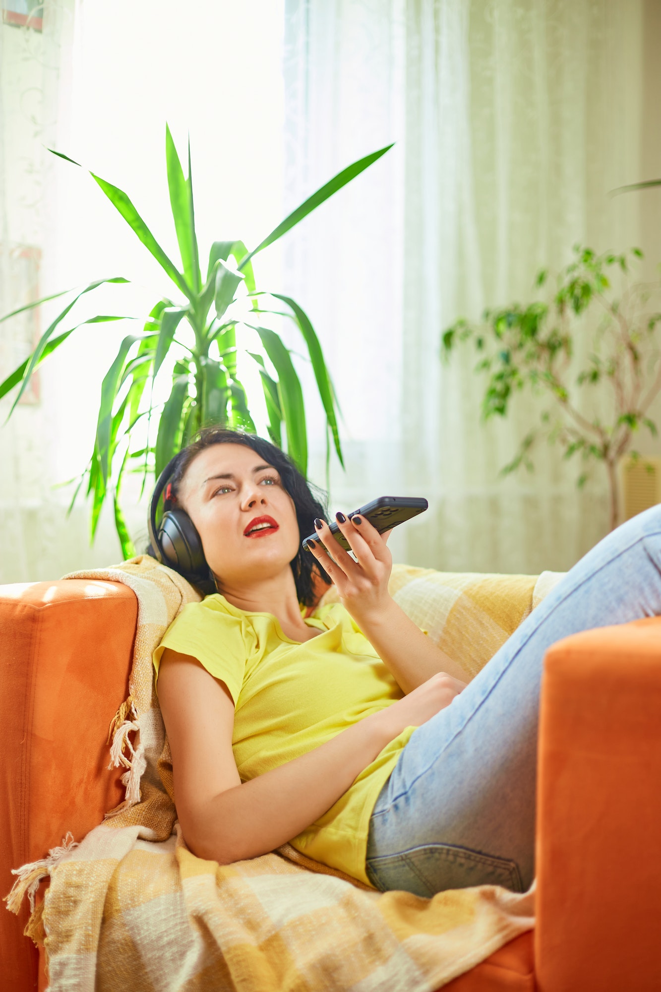 Infirmière allongée dans un canapé avec des écouteurs sur les oreilles et un téléphone dans la main